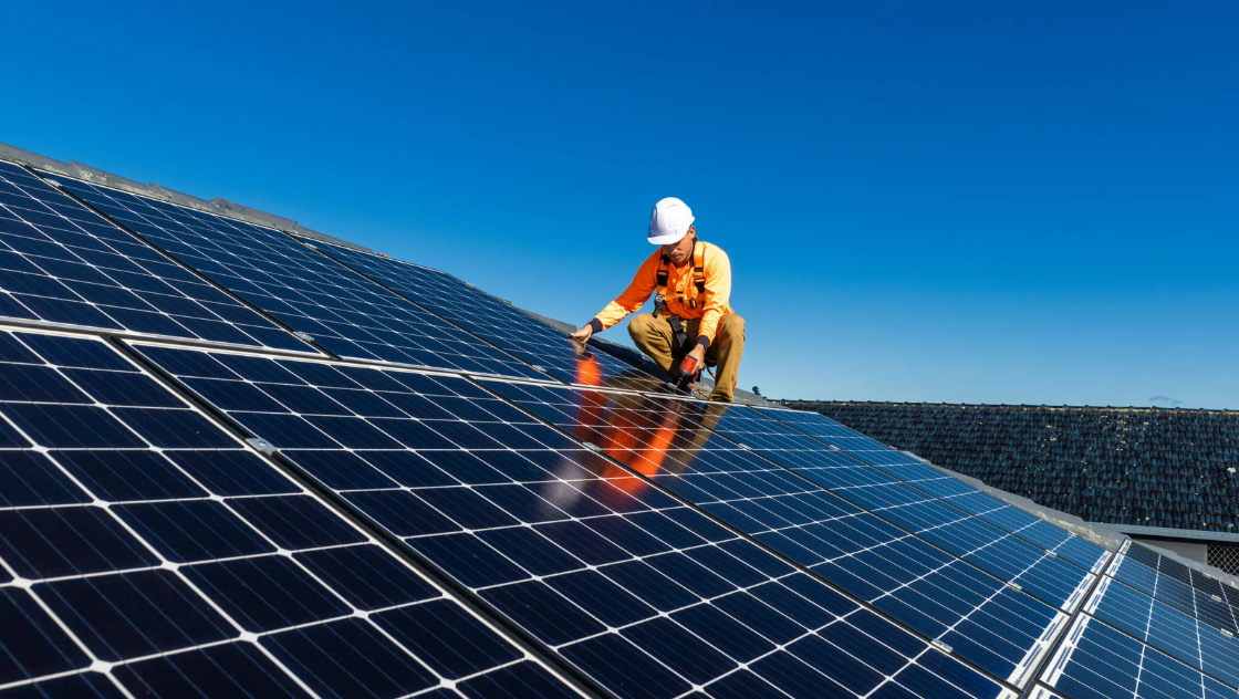Instalador trabalhando em painéis solares no telhado