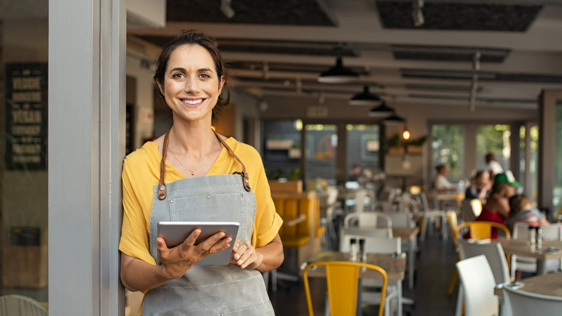 Empreendedora sorrindo com tablet em seu comércio